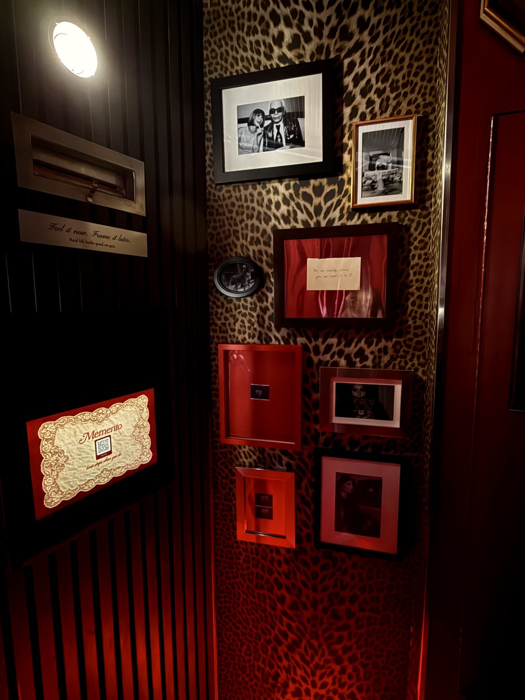 Inside the Memento space, leopard wallpaper with framed photographs and red velvet accents