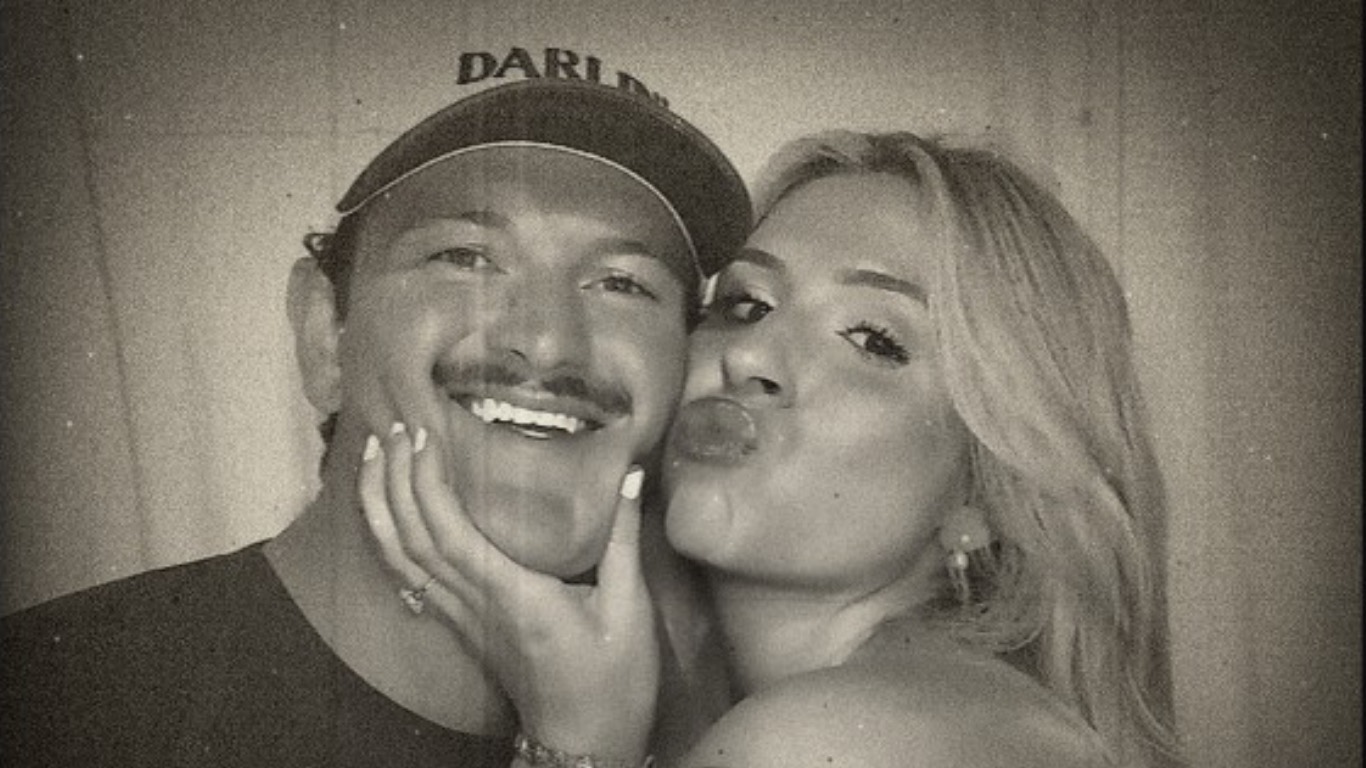 A couple laughing in the booth, one in a cap.