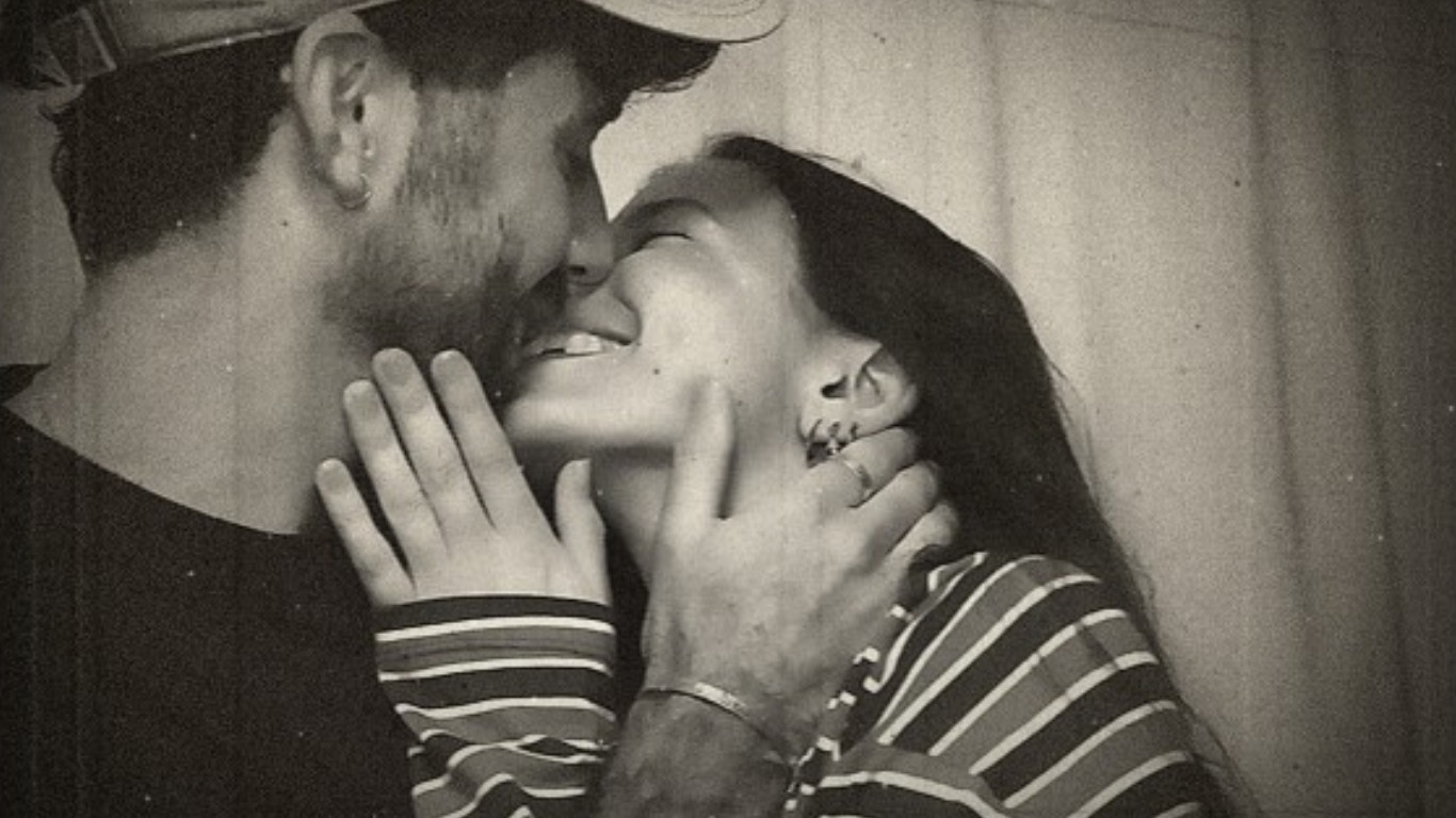A couple holding each other's faces, laughing.