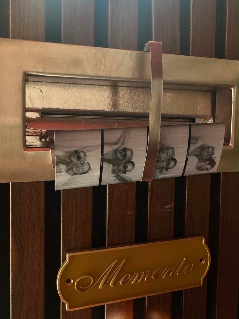 Photo strips emerging from the brass slot beneath the engraved Memento plaque.