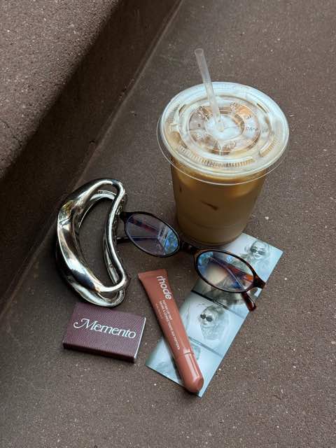 An iced coffee, sunglasses, a Memento matchbook and a photo strip on a stoop.
