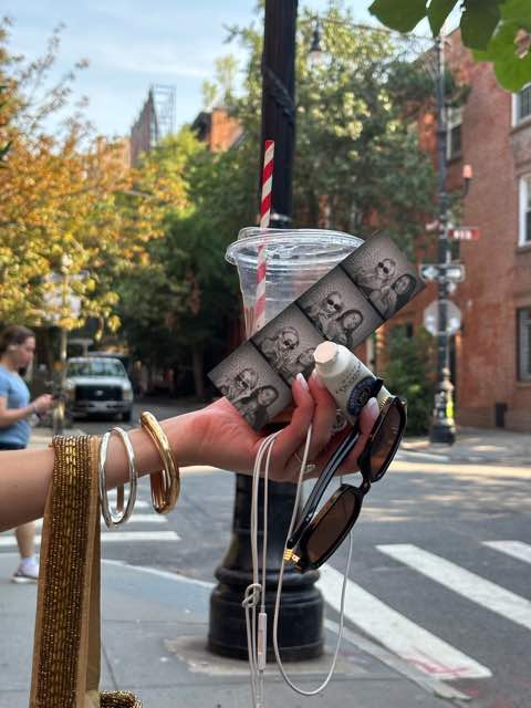 Photo strips held up against a leafy West Village street corner.